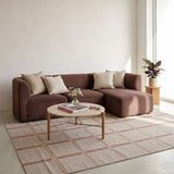Braunes skandinavisches Ecksofa mit rechter Chaiselongue und hellen Kissen auf gemustertem Teppich in einem hellen Wohnzimmer von sackit | Fjord Sofa - Chaise Right - Sealife Ivory | SACKit