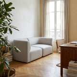 Helles Fjord Sofa für zwei Personen von sackit in einem skandinavischen Wohnzimmer mit Fenster, Holzboden und natürlicher Einrichtung | Fjord Sofa - 2 seater - Cosmo Olive | SACKit
