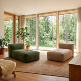 Modulares boneless Sofa im Wohnzimmer mit grünen und beigefarbenen Polsterelementen auf einem Teppich vor großen Fenstern mit Blick in den Wald