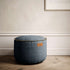Runder Canvas Pouf in Petrol mit handgenähten Stichen und robuster Oberfläche.