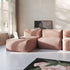 Rosafarbene modulare boneless Couch mit weicher Rippentextur und Lounger in hellem Wohnzimmer mit großen Fenstern und floralem Teppich von sackit
