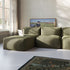 Olivegrüne modulare Boneless Couch mit gerippter Polsterung und passendem Lounger in einem hellen Wohnzimmer mit Kunstwerk und Teppich
