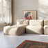 Cremefarbenes modulares Sofa ohne Gestell von sackit in hellem Wohnraum mit weichen Sitzpolstern, Tageslicht, Kunstwerk und gemustertem Teppich