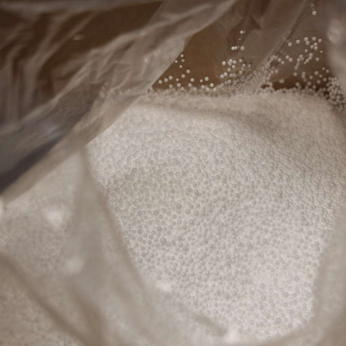 Weiße EPS-Kugeln als Nachfüllpackung für Sitzsäcke, 100 Liter Inhalt in transparenter Verpackung.
