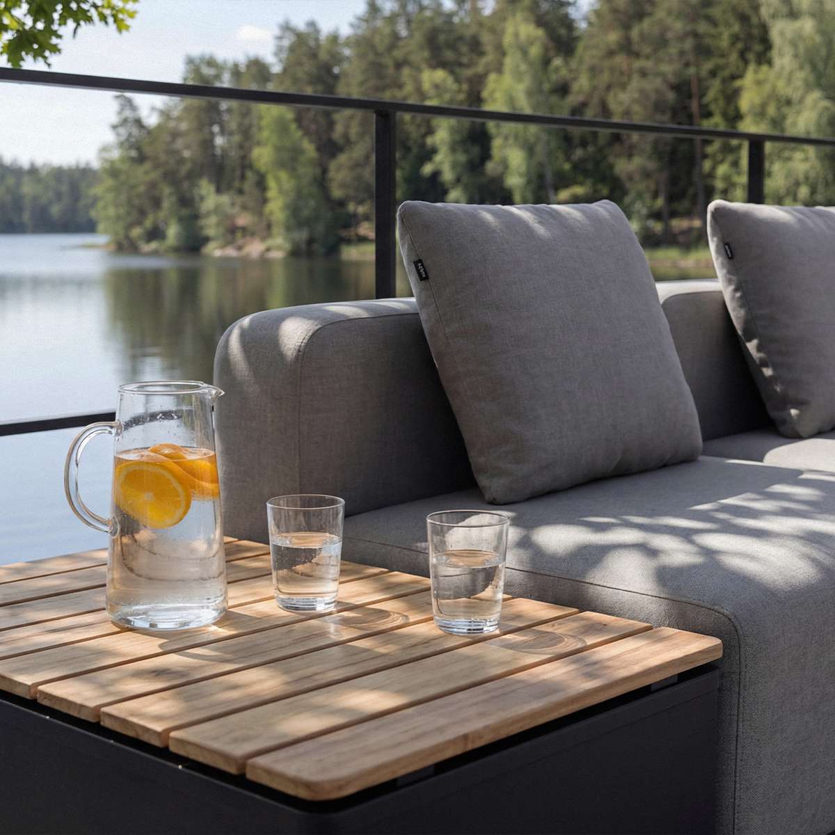 Graues dreisitziges Outdoor Lounge Sofa von sackit mit weichen Kissen und integrierter Teakholz Ablage am See unter freiem Himmel | Cobana Lounge Sofa - 3 seater w/ Patio Storage Table - Kirra Sand Mit Armlehnen Mit Hocker | SACKit