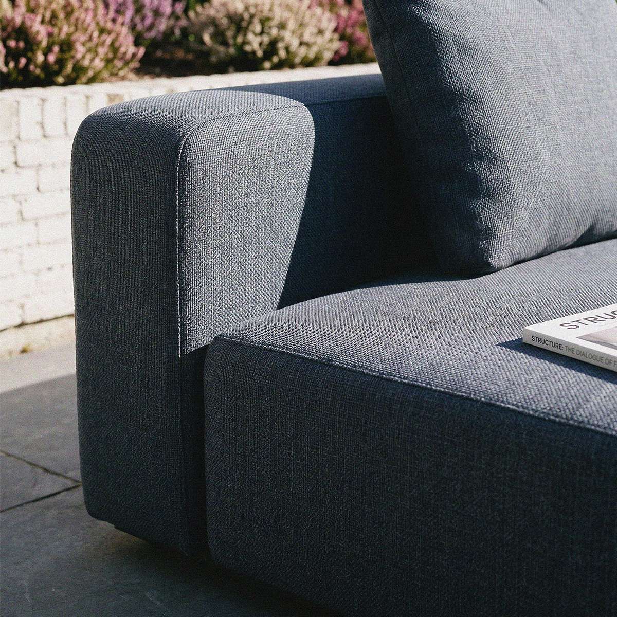 Detailaufnahme eines dunkelgrauen Outdoor Sofas von sackit mit weicher Polsterung und klaren skandinavischen Linien im Gartenbereich | Cobana Lounge Sofa - 4 seater corner sofa - Kirra Sand Mit Armlehnen | SACKit
