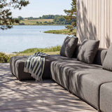 Graues sackit Cobana Outdoor Loungesofa mit dreisitzigem Sofa und Chaiselongue auf einer Holzterrasse am Wasser unter schattenspendenden Bäumen | Cobana Lounge Sofa - 3 Seater Chaise - Kirra Sand Mit Armlehnen | SACKit