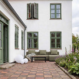 Olivgrünes dreisitziges Outdoor Sofa von sackit im begrünten Innenhof mit skandinavischen Linien und passendem Couchtisch auf historischem Ziegelpflaster | Cobana Lounge Sofa - 3 seater - Kirra Sand Mit Armlehnen Mit Hocker | SACKit