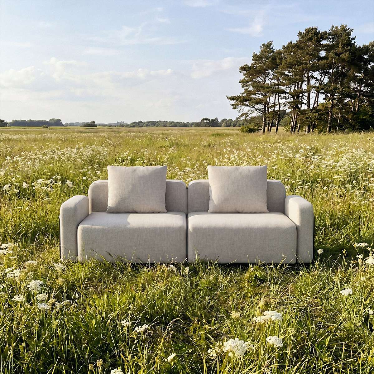 Hellgraues zweisitziges Outdoor Sofa von sackit in einer blühenden Wiese mit Kissen und skandinavischem Design unter freiem Himmel | Cobana Lounge Sofa - 2 seater - Kirra Sand Ohne Armlehnen Mit Hocker | SACKit