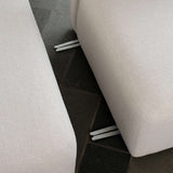 Nahaufnahme eines hellen skandinavischen Sofas mit sichtbaren Metallverbindern zwischen den gepolsterten Segmenten auf dunklem Fliesenboden | Fjord Sofa - Chaise Left - Cosmo Clay | SACKit