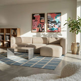 Beiges skandinavisches Ecksofa mit rechter Chaise von sackit in hellem Wohnzimmer mit Couchtisch Teppich Pflanzen und farbenfrohen Bildern an der Wand | Fjord Sofa - Chaise Right - Sealife Ivory | SACKit