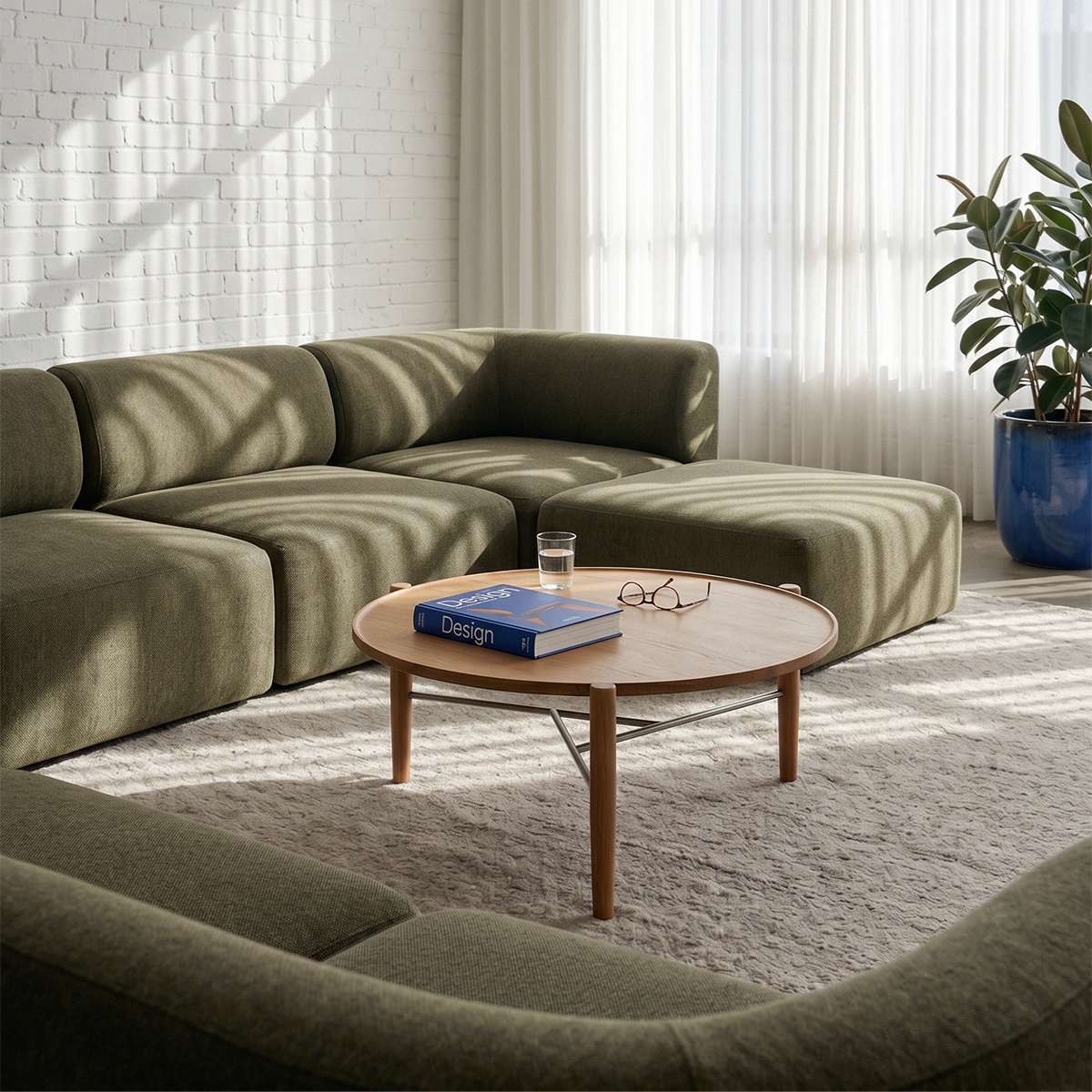 Olivgrünes modulares Sofa von sackit in einem hellen skandinavischen Wohnzimmer mit rundem Couchtisch aus Holz Teppich und Zimmerpflanze | Fjord Sofa - Corner Section Left - Cosmo Clay | SACKit