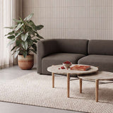 Skandinavisches Wohnzimmer mit dunkelgrauem Fjord Sofa für zwei Personen von sackit neben runden Couchtischen auf einem hellen Teppich und mit großer Zimmerpflanze | Fjord Sofa - 2 seater - Cosmo Olive | SACKit