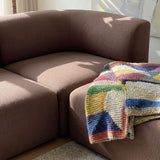 Braunes Ecksofa mit weichen Polstern und farbenfroher gestrickter Decke im warmen Sonnenlicht eines skandinavischen Wohnraums | Fjord Sofa - Corner Section Right - Cosmo Mustard | SACKit
