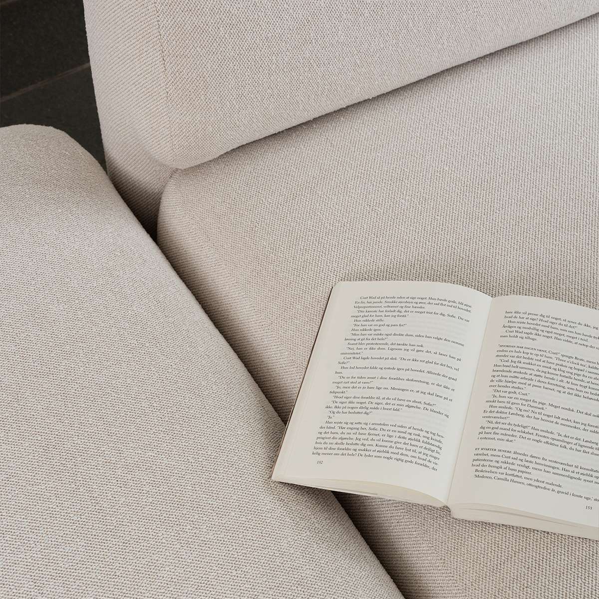 Nahaufnahme eines hellen Fjord Sofas von sackit mit offenem Buch auf der Sitzfläche und weicher skandinavischer Stoffpolsterung | Fjord Sofa - 2 seater w/ open end - Cosmo Terracotta Links | SACKit