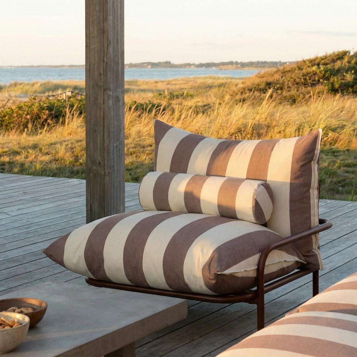 Gestreifte Outdoor Kissen von sackit auf einem Loungesessel am Meer mit zylindrischem Bolster und gemütlicher Sitzauflage auf einer Holzterrasse | Outdoor Cushion - Bolster - Renesse Olive | SACKit