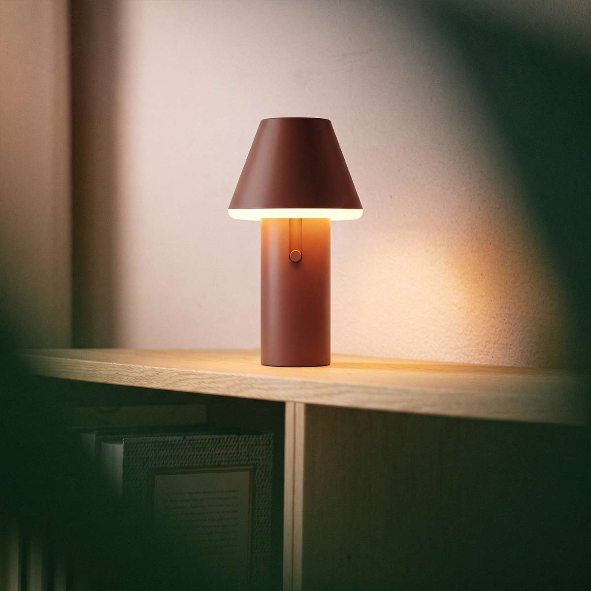 Kabellose sackit Tischleuchte Cone aus braunem Aluminium auf einem Holzmöbel mit warmem Licht für gemütliche Innenräume