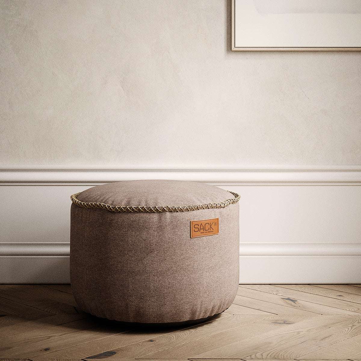 Brauner Canvas Pouf von sackit als runder Sitzhocker mit dekorativer Kedernaht in einem stilvollen Innenraum auf Holzboden | Canvas Pouf - Canvas Petrol | SACKit