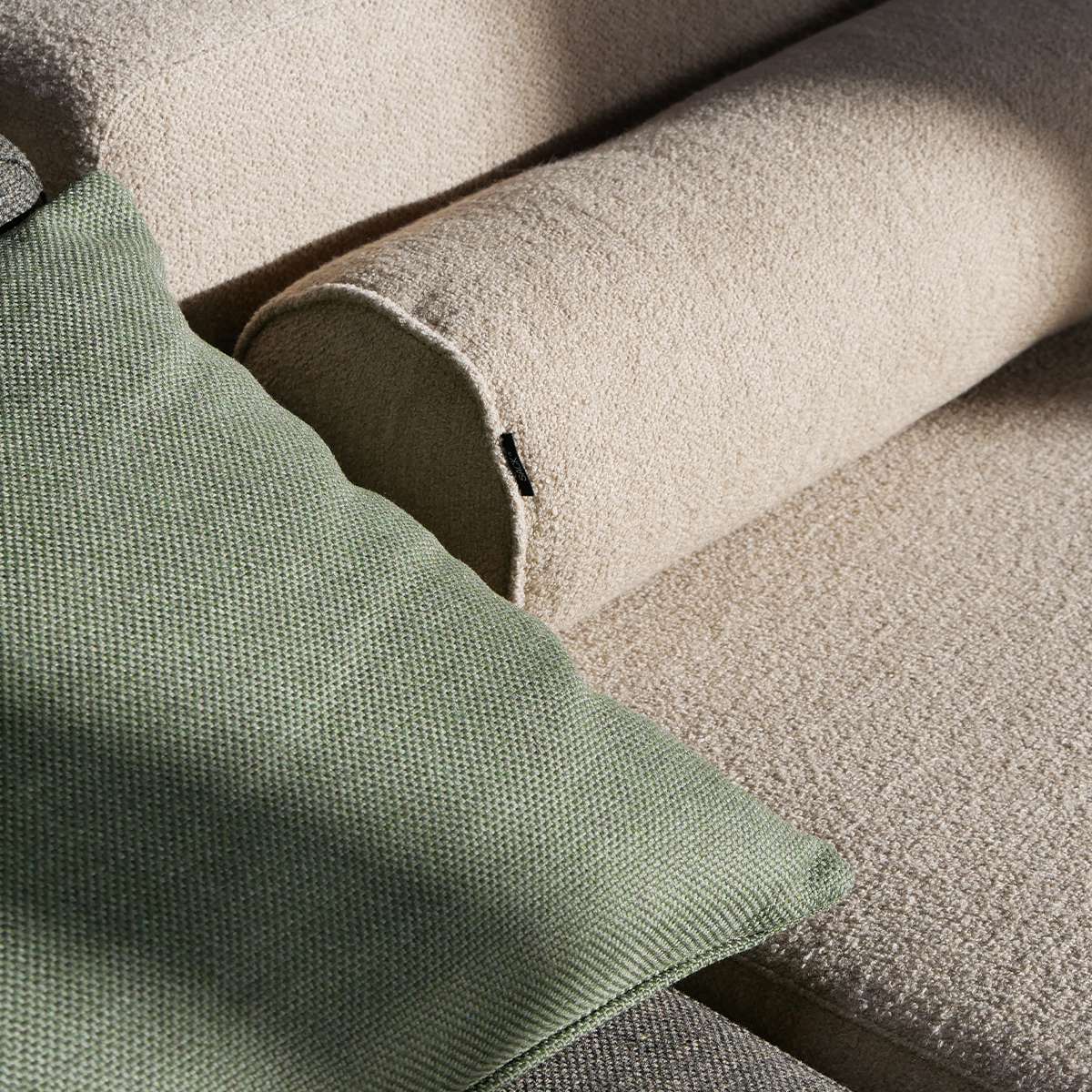 Nahaufnahme eines sandfarbenen Outdoor Sofas mit weichen Polstern und grünem Kissen von sackit im skandinavischen Design für langlebige Gartenmöbel