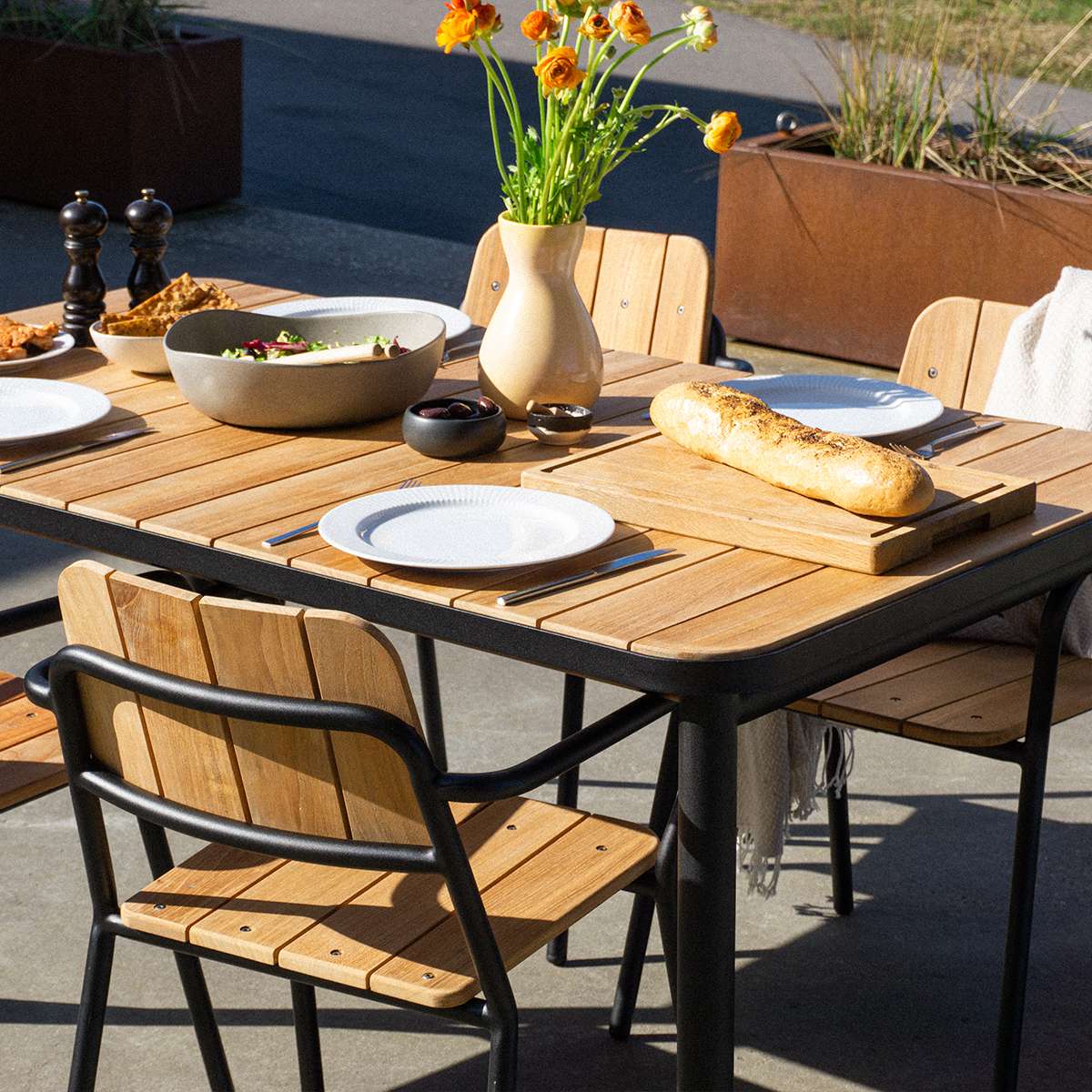 Schwarzer Kirra Patio Chair aus pulverbeschichtetem Aluminium und Teakholz auf einer Terrasse | Kirra Patio Chair - Black | SACKit