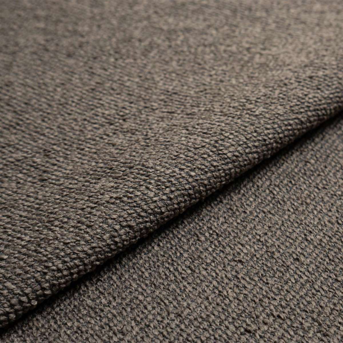 Nahaufnahme des strukturierten graubraunen Bezugsstoffs des Fjord Sofas von sackit germany mit hochwertiger Webstruktur und weicher Oberfläche